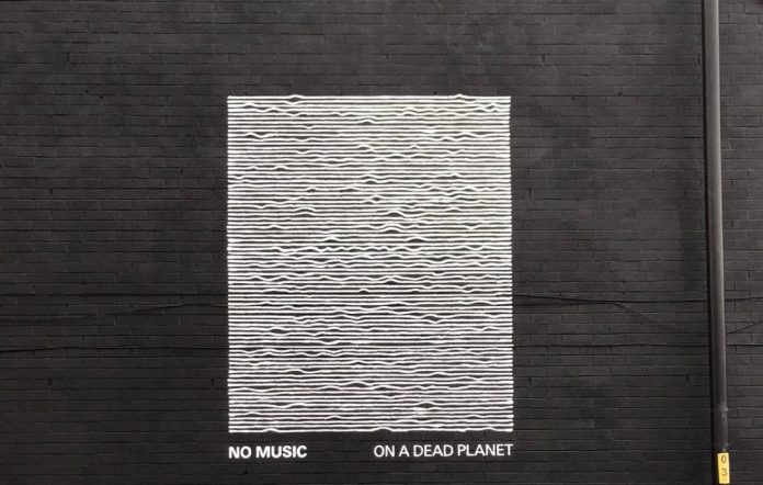 The No Music on a Dead Planet mural on a Manchester building, with the pulse lines gradually flattened