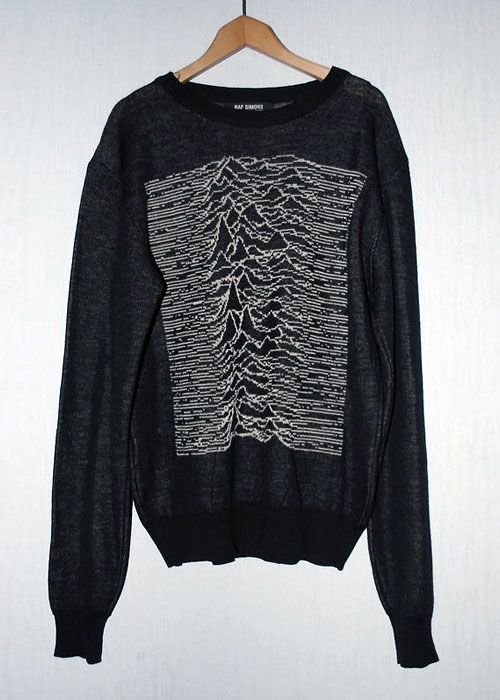 A black Raf Simons sweater on a wooden hanger with white pulse lines knitted across the front