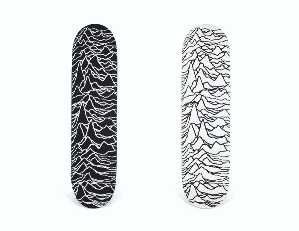 A black and a white Supreme skateboard deck carrying the Unknown Pleasures pulse graphic